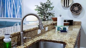 Cocina con encimeras de granito, pileta de acero inoxidable y grifo moderno.