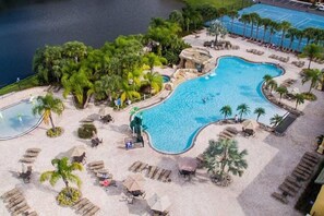 An aerial view of a resort with a large swimming pool, lounge areas, and a tennis court. - Disney Getaway Oasis: 4BR Townhome, Heated Pool & BBQ, Perfect for Families! (Kissimmee)