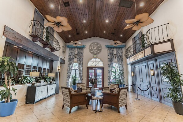 A lobby with a high ceiling, wooden beams, a reception desk, seating area, and a cinema sign.