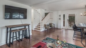 Una cucina moderna con isola in legno, pareti bianche e una scala che conduce a un balcone.