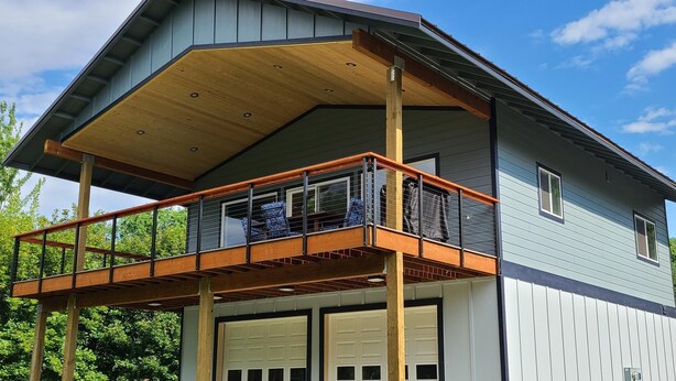 A two-story house with a balcony, a garage, and a clear sky. - Spectacle Lake Waterfront Retreat Chalet (Tonasket)