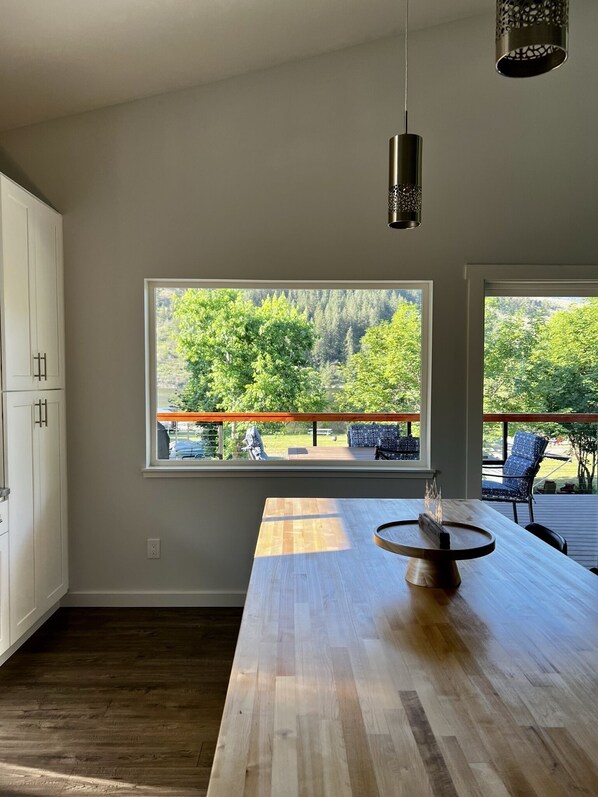 Una cocina moderna con encimera de madera, horno empotrado y un amplio ventanal con vistas a una terraza y vegetación.