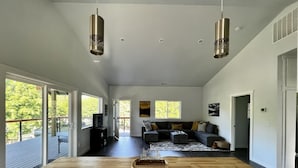 A spacious living room with a large wooden table, a sectional sofa, and two pendant lights. - Spectacle Lake Waterfront Retreat Chalet (Tonasket)
