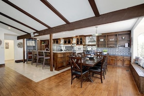 A spacious kitchen with wooden cabinets, a dining area with a large table and chairs, and a built-in island with a sink.