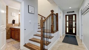 Een trap met houten treden en zwarte balustrades, die leidt naar een plateau met een zwarte mat.