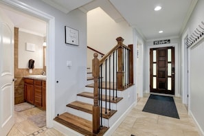 A staircase with wooden steps and black balusters, leading to a landing with a black mat.