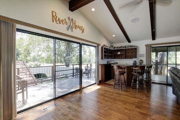 A spacious kitchen with a large island, sliding glass doors leading to a deck, and a bar area with stools.