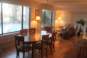 Un área de comedor con una mesa y sillas de madera, un sofá y una planta en maceta.