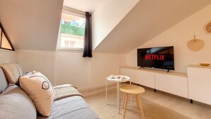 A modern living room with a sofa, a small table, a TV, and a window with curtains. - N&J -  VIEUX NICE SUITE - Old Town - Close sea (Niza)