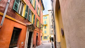 A narrow street with colorful buildings, a clear sky, and a visible blue sign. - N&J -  VIEUX NICE SUITE - Old Town - Close sea (Niza)