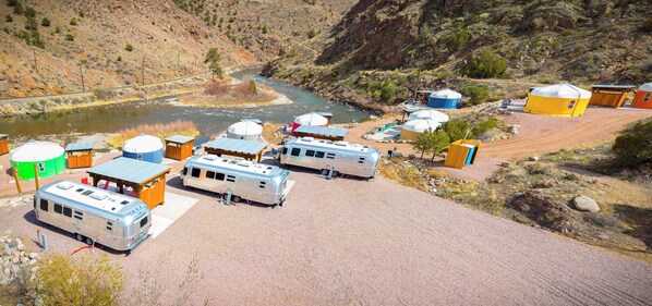 Un terrain de camping proposant des emplacements pour camping-cars, des yourtes et situé près d’une rivière.
