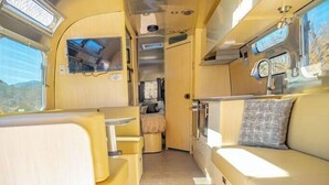 Ein kompaktes Wohnmobil-Interieur mit einer Küchenzeile, einer Sitzecke und einem kleinen Fenster.