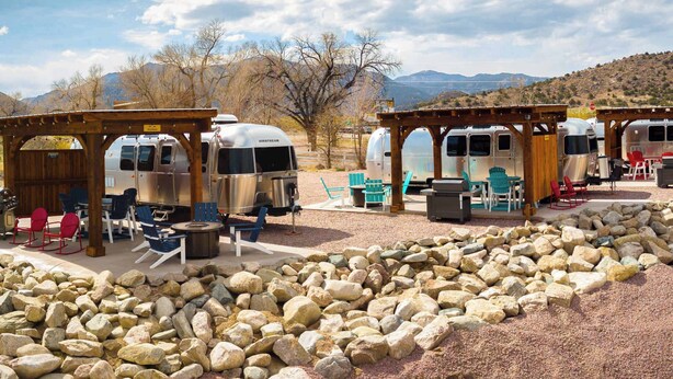 A campground with RVs, outdoor seating, and a rocky landscape.