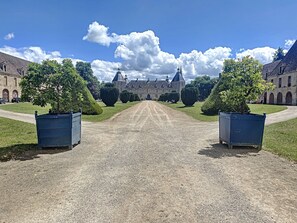 Ein symmetrischer Weg führt zu einem großen, historischen Gebäude mit mehreren Türmen und einem zentralen Eingang.