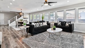 A spacious living room with a black sectional sofa, a round coffee table, and a patterned rug. - Amazing and Comfortable Home in Grand Prairie! (Grand Prairie)