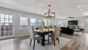 A spacious dining area with a dark wood table, light grey upholstered chairs, and a geometric patterned rug. - Amazing and Comfortable Home in Grand Prairie! (Grand Prairie)