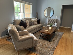 Sala de estar com sofá, poltrona, mesa de centro e espelho.