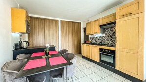 A compact kitchen with wooden cabinets, a black countertop, and a tiled floor. - Annecy 1 bedroom Apt With Balcony (Annecy)