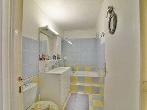Bathroom features a white sink and bathtub, complemented by checkered tiles and a wall-mounted mirror with overhead lighting.