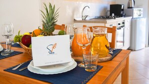 A breakfast setting with fruits, a pitcher of orange juice, and a menu card on a wooden table in a kitchen. - SUD12 - Case vacanze (Mazara del Vallo)