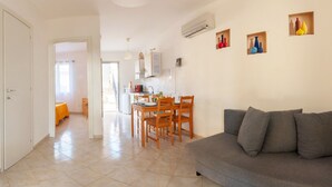A modern living room with a grey sofa and a dining area with wooden chairs and a table. - SUD12 - Case vacanze (Mazara del Vallo)