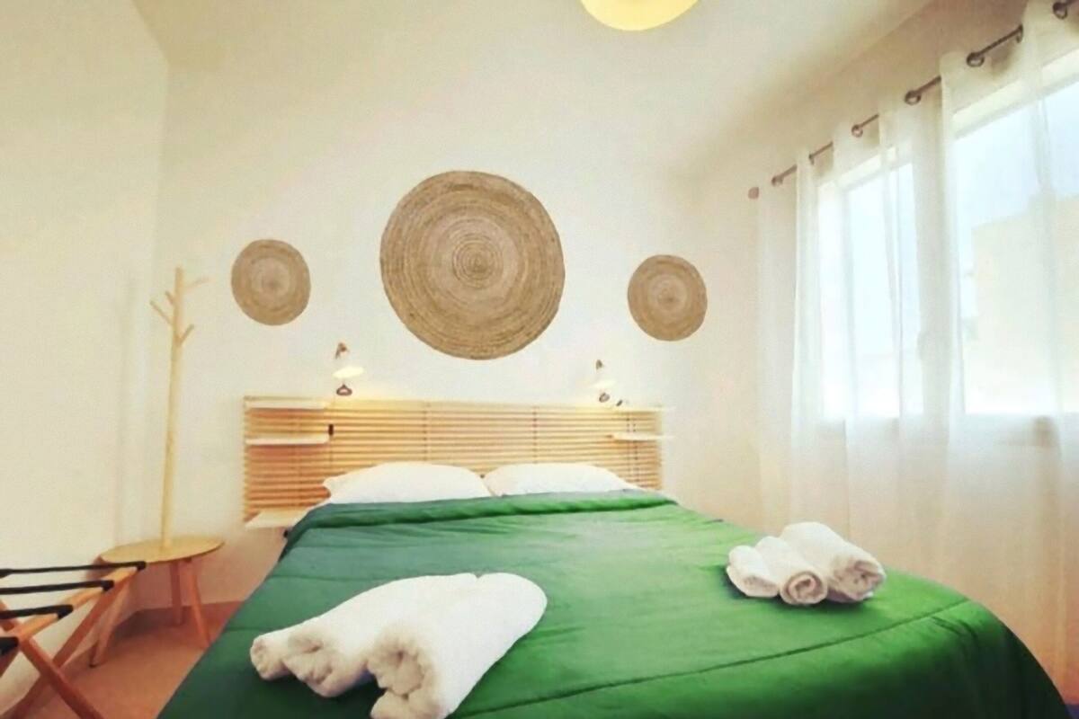 A hotel room with a bed, a chair, and a window with curtains.