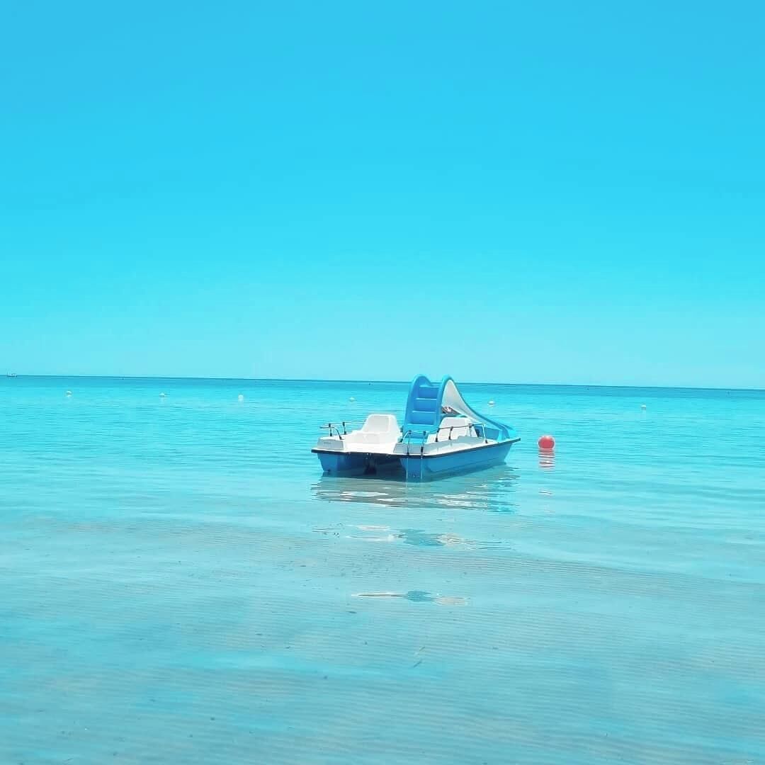 Una pequeña embarcación sobre aguas tranquilas y cristalinas, bajo un cielo despejado.