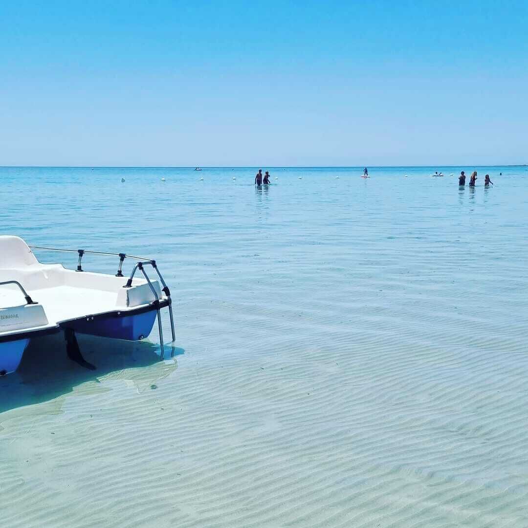A clear blue sea with a boat docked on the shore.