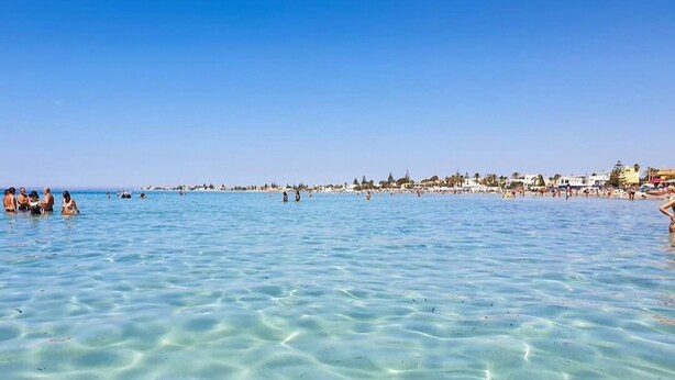 A beach with clear shallow waters and a distant shoreline with buildings. - SUD12 - Case vacanze (Mazara del Vallo)