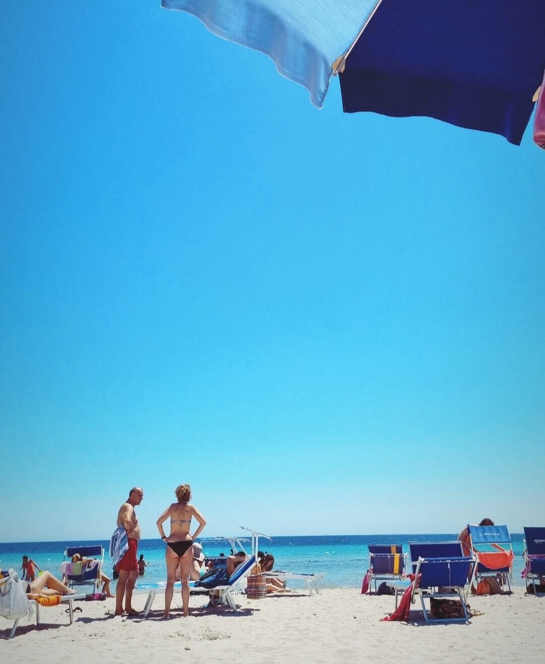 A beach with sun loungers and umbrellas.