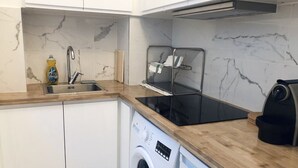 A compact kitchen with a built-in washing machine, a sink, and a stove.