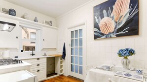 A modern kitchen with white cabinetry, a gas stove, and a dining area with a white table set for two.