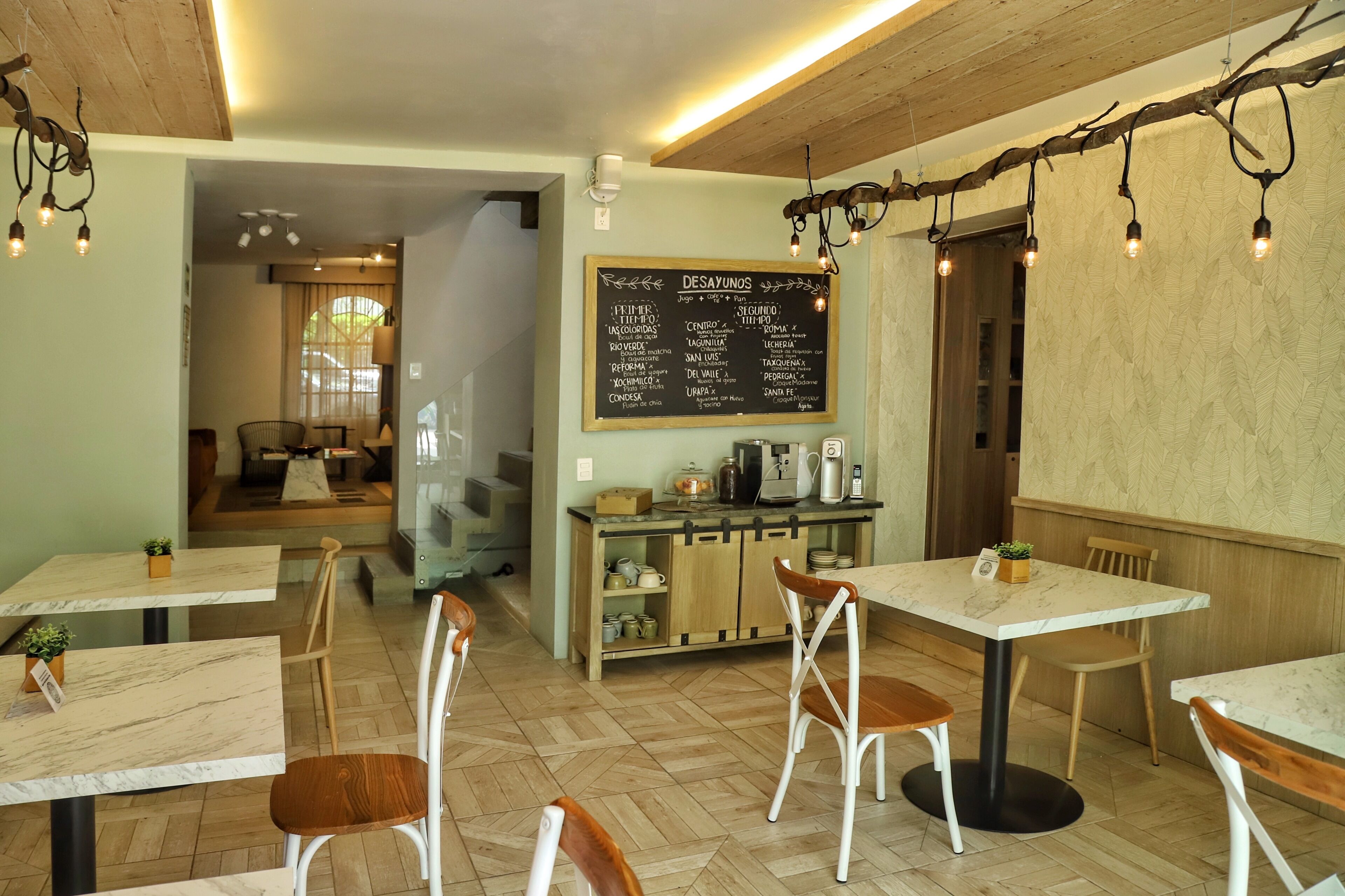 Interior de restaurante com mesas e cadeiras de madeira, um menu em lousa e um espaço de estar acolhedor.