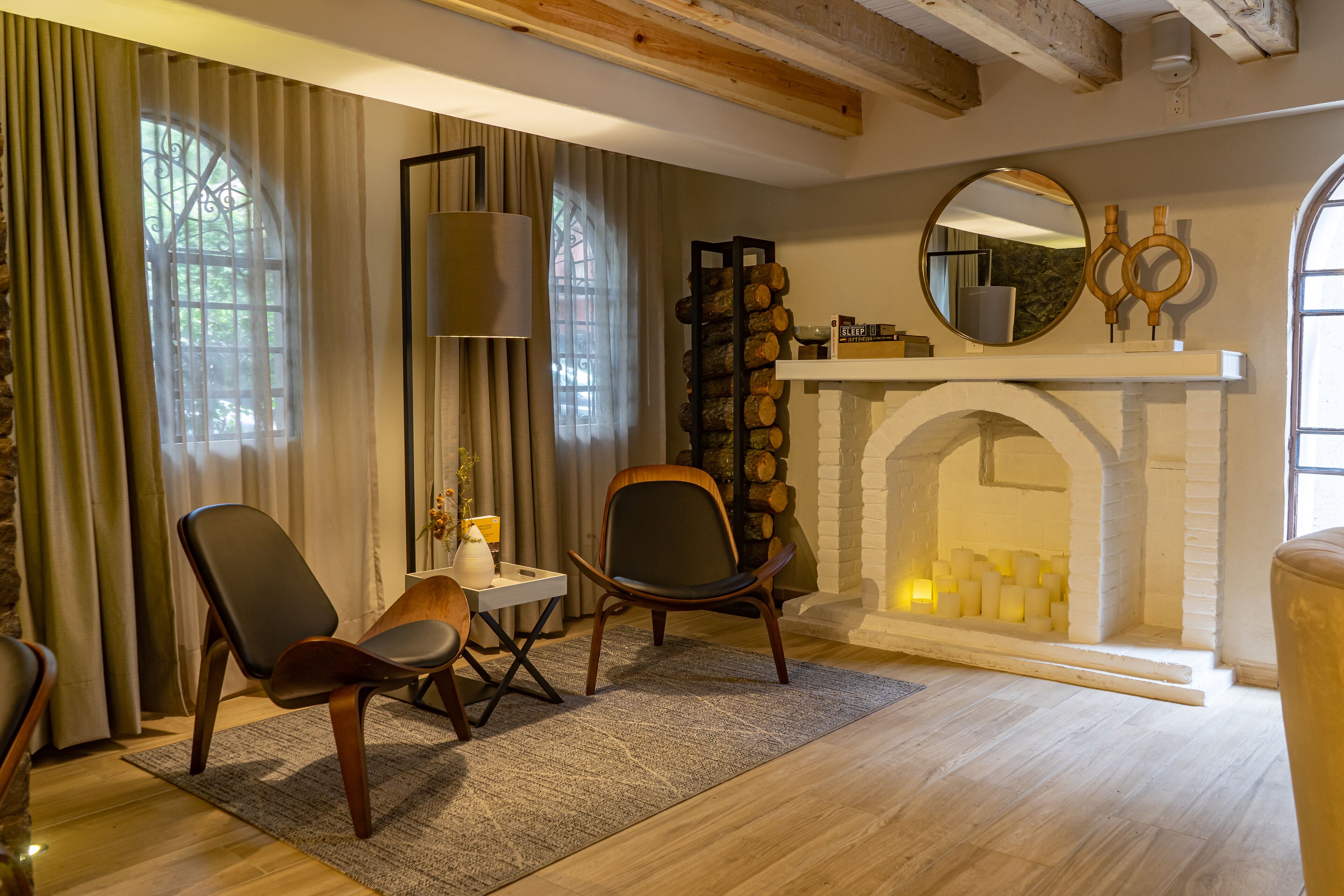 Una sala de estar acogedora con dos sillones de cuero, una mesita, una chimenea y un espejo grande encima.