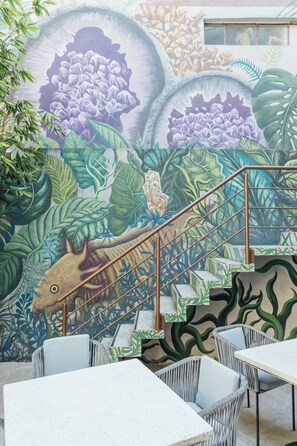 Une fresque représentant un escalier et un espace détente avec des sièges.