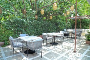Une terrasse extérieure avec des meubles en osier et des paniers suspendus.