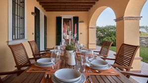A dining table set for six with wooden chairs, a white pitcher, and red candles. - Villa Ardea Exclusive Holigarda (Soiano del Lago)