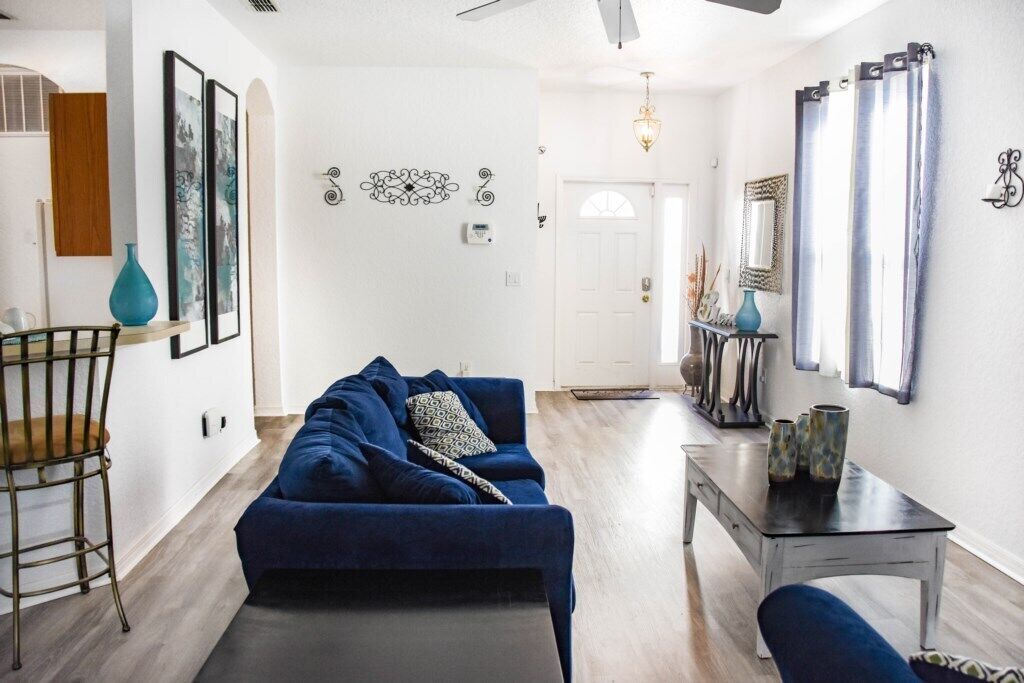 Un salon avec un canapé bleu foncé, une petite table ornée d’objets décoratifs et un fauteuil.