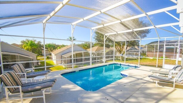 A covered outdoor swimming pool with lounge chairs and a clear view of the surrounding neighborhood. - HR135HS - Highlands Reserve - 4 beds pool home close to Disney (Davenport)