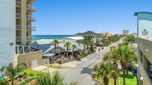 Un hotel costero con vistas a la playa, mobiliario exterior y palmeras.