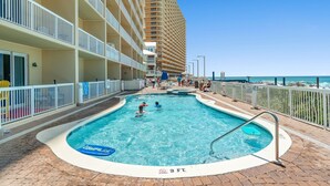 Zona de piscina de hotel con vista despejada a la playa, una torre de salvavidas y un indicador de profundidad de 0.9 metros.