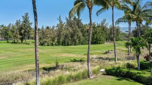 A golf course with palm trees and a clear blue sky.