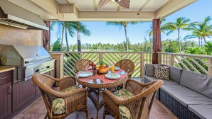 An outdoor patio with a grill, wicker chairs, a round table set for dining, and a sofa.