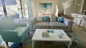 Un salon moderne comprenant un canapé, une table basse et un coin repas avec des chaises.