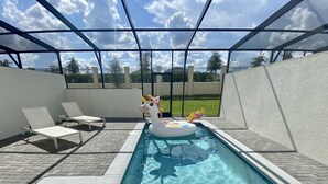 Une piscine équipée de chaises longues et d’un flotteur en forme de licorne.