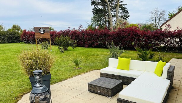 An outdoor seating area with a white sofa, two side tables, and a decorative metal planter. - Maison Familiale " L'abbé Garo " (Port-en-Bessin-Huppain)