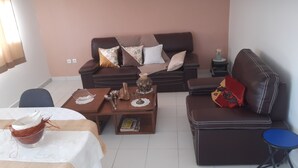 A living room with a brown sofa set, a coffee table with decorative items, a small side table, and a blue stool. - Balaou Villa facing the sea (anse d'arlet)