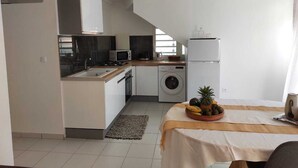 A compact kitchen with a sink, microwave, stove, and washing machine. - Balaou Villa facing the sea (anse d'arlet)