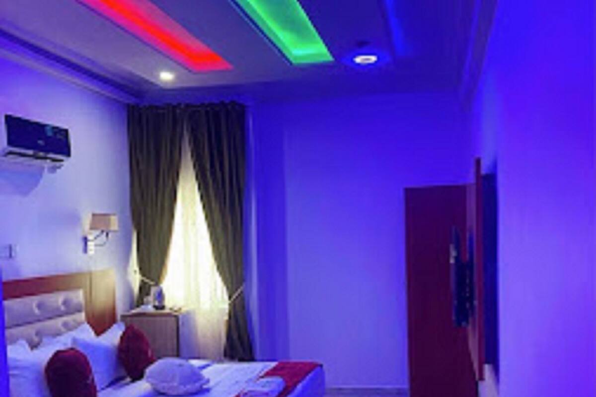 A hotel room with a bed, a nightstand, a lamp, and a TV on the wall.