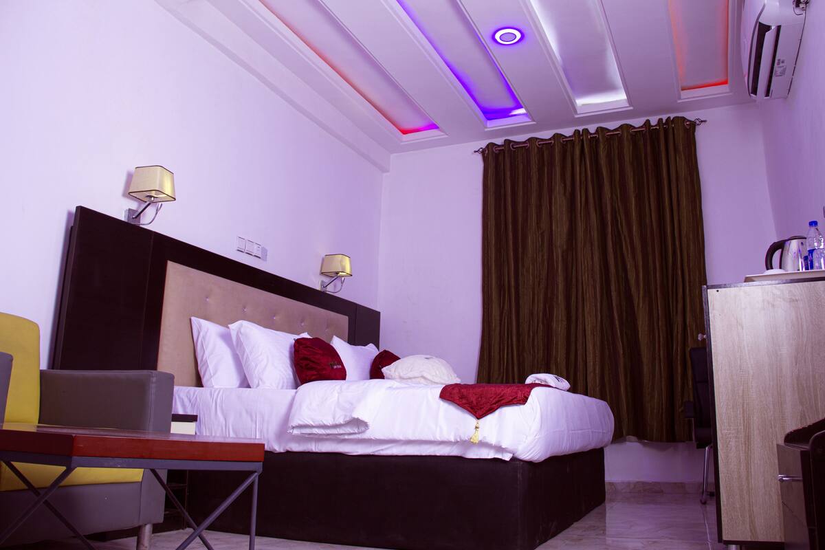 A hotel room with a bed, bedside lamps, a desk, and a wardrobe.